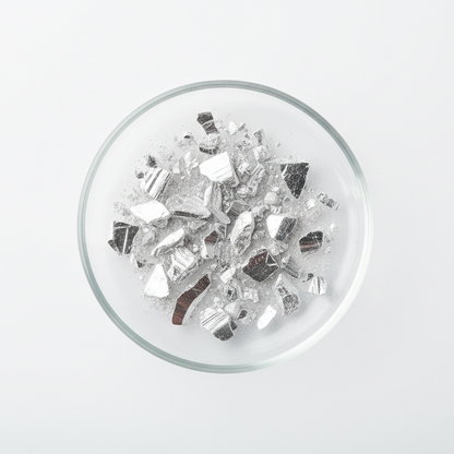 A white background, pharmaceutical photo with a glass disc. Inside the glass disc is powdered/small bits of elemental magnesium